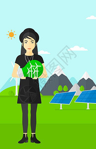 绿色发电厂旁手握绿色概念灯泡的女子图片