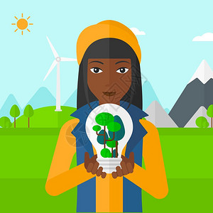 手握咖非一名绿色发电厂旁手握绿色概念灯泡的非裔女子设计图片