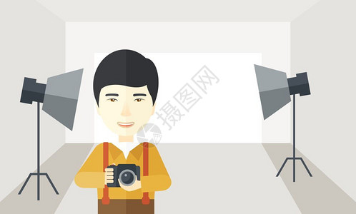 亚洲摄影师拿着相机站在摄影棚里图片