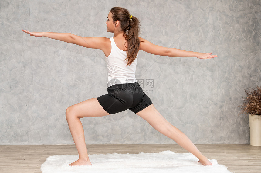年轻美女在家里客厅的地毯上做瑜伽锻炼图片