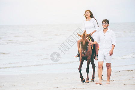 男生牵恋人骑着的马在海边散步图片