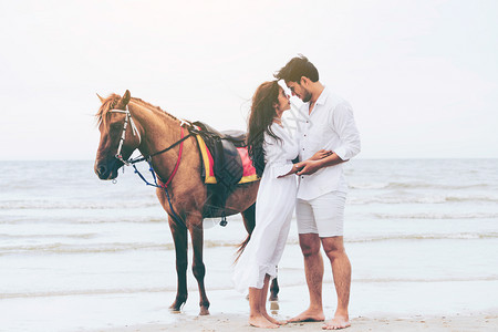 海边一对情侣在一匹马旁边相拥对视图片
