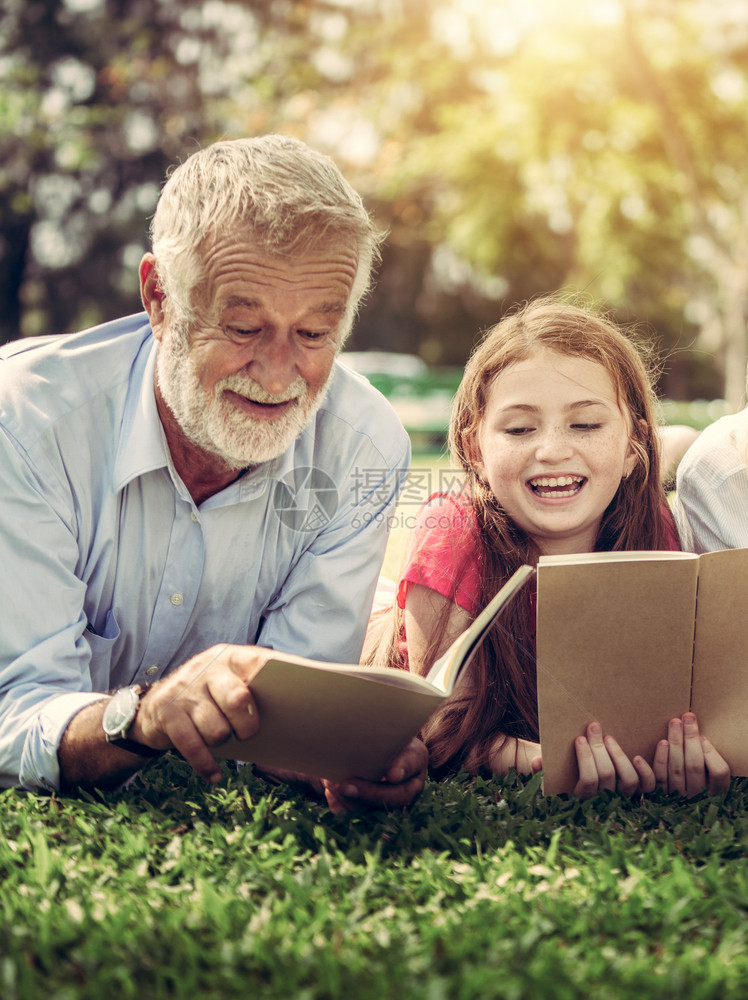 爷爷与小女孩在公园草地看书图片