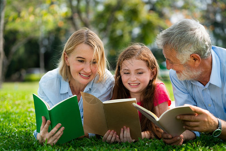 一家人趴在公园草地上看书背景图片