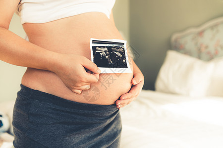 年轻孕妇在怀期间拿着四维照片图片