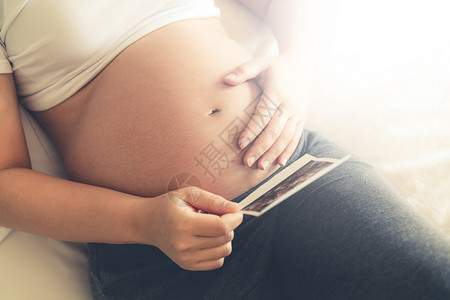 年轻孕妇在怀期间在看四维照片背景图片