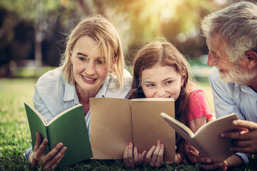 快乐的家庭在公园草地看书学习图片