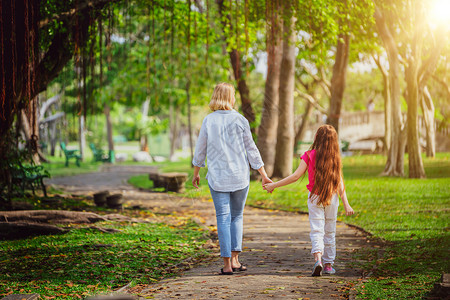 户外公园母亲和女孩牵手散步图片