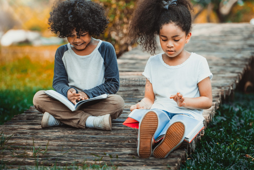 公园里快乐的小男孩小女孩一起阅读图片