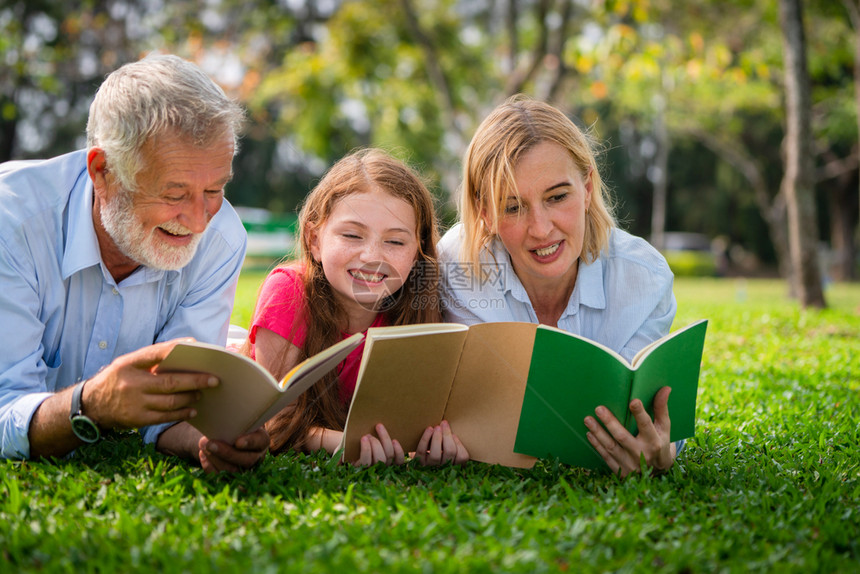 快乐的家庭一起在公园绿草地上阅读书籍图片