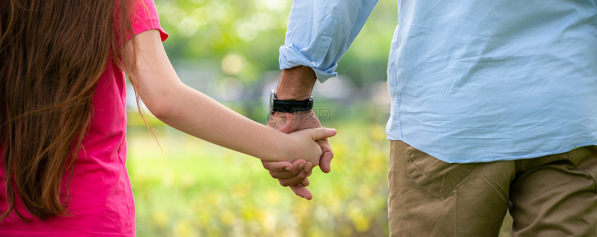 父亲和女儿手牵手在公园散步图片
