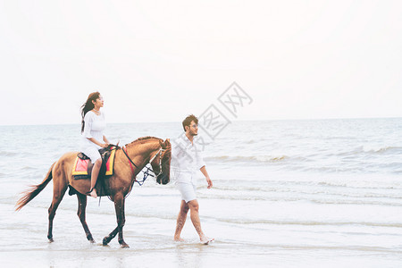 男生牵着马在海边散步背景图片