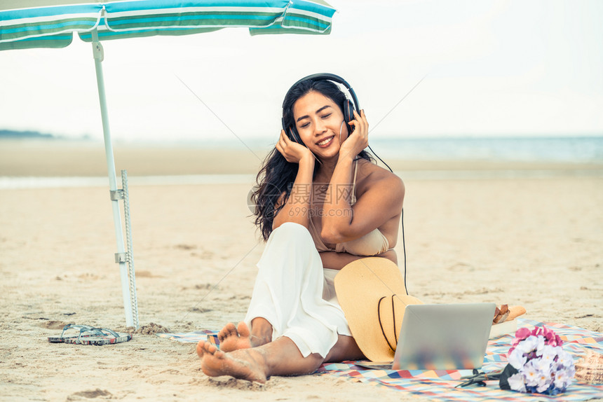 夏天坐在热带沙滩上的年轻女子假期旅行图片