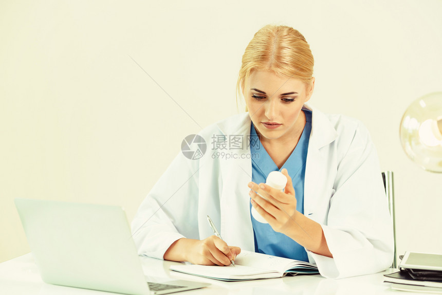 女医生在办公室桌子上撰写医疗报告图片