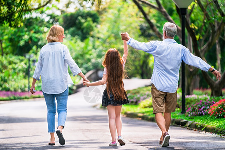 快乐的幸福家庭在夏天公园的路上牵手走路图片