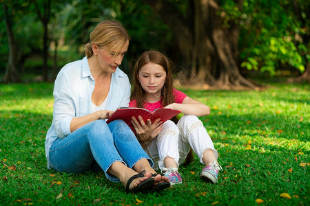 公园中一起看书的母女背景图片