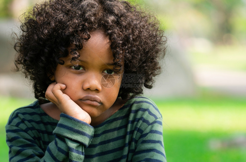 坐在公园里的非洲小孩情绪消极的男孩儿童麻烦的概念图片