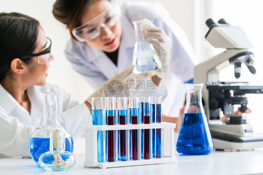 科学家们穿着实验室大衣在工作同时审查测试管和科学仪器的生物化样本图片