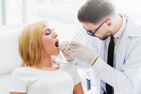 洗牙植牙年轻英俊的牙医检查在科诊所坐医椅子上的幸福妇女病人牙齿科护理概念背景
