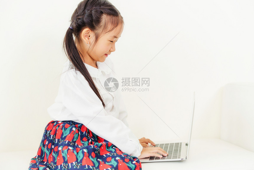 孩子使用笔记本电脑坐在白色沙发上图片