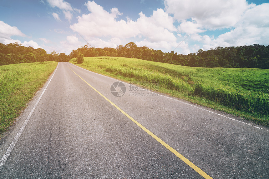 夏日蓝天白云下穿过绿草地的高速公路图片