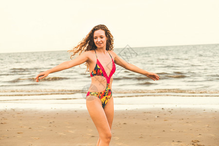 泳装步行身穿泳衣的快乐年轻女子暑假在热带海滩度假背景