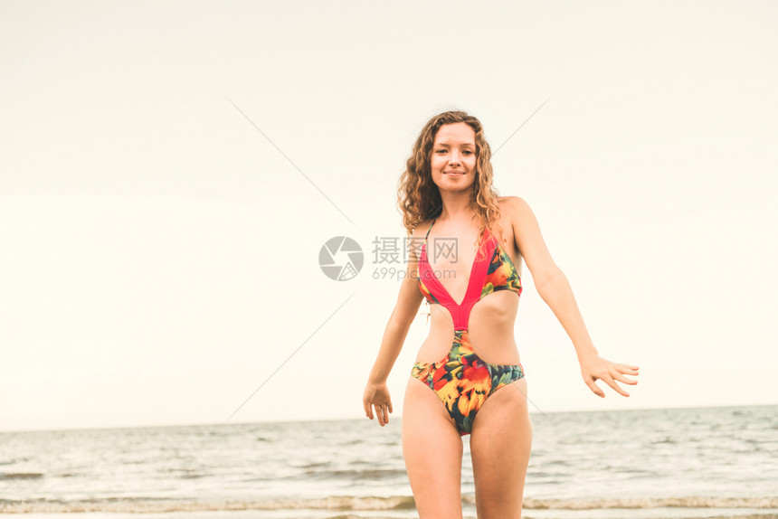 暑假身穿泳衣的快乐年轻女子在热带海滩图片