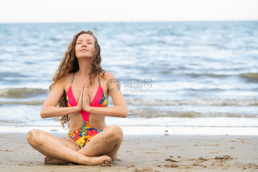 年轻女在沙滩上做瑜伽图片