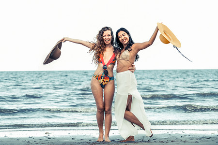 穿着比基尼的快乐妇女一起在夏季假期热带沙滩上跳舞图片