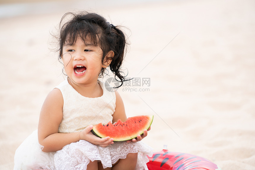 可爱的孩子在海滩上吃西瓜图片
