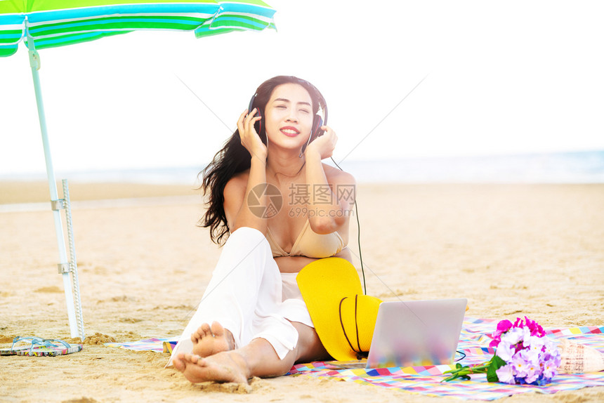 夏天坐在热带沙滩上的年轻女子图片