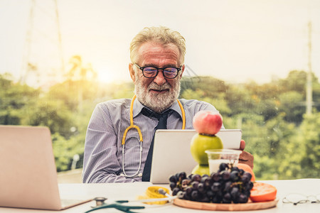 高级男营养学医生在用笔记本电脑工作饮食和健康概念图片