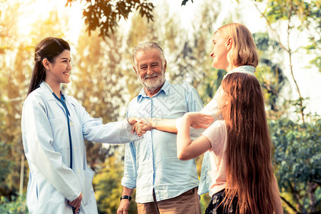 快乐健康的家庭和医生在公园握手交谈图片