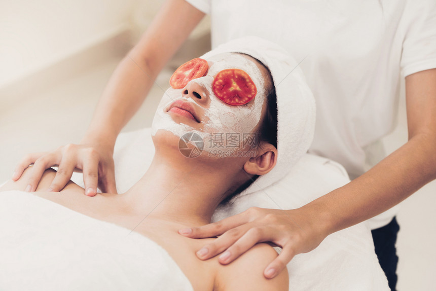 接受面部番茄奶油面膜美容皮肤护理的美女图片