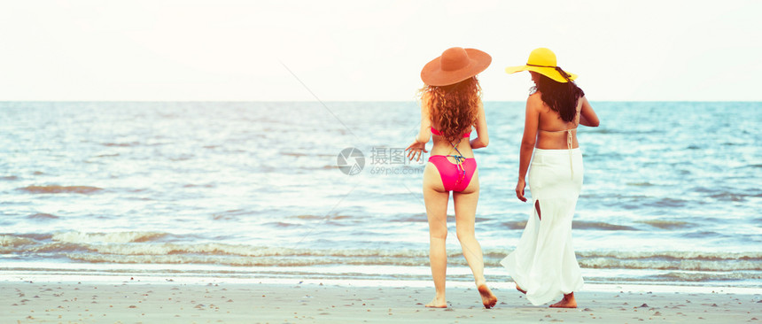 暑假穿着比基尼的快乐妇女一起行走在热带沙滩上晒太阳图片