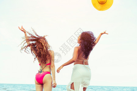 暑假穿着比基尼的快乐妇女一起在热带沙滩上跳跃图片