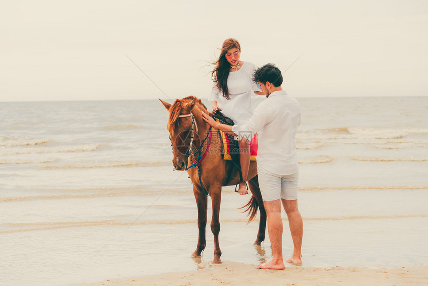暑假年轻夫妇在热带海滩骑马度蜜月图片