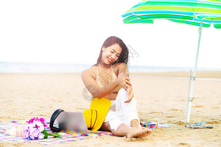 夏天坐在热带沙滩上快乐的年轻女子图片