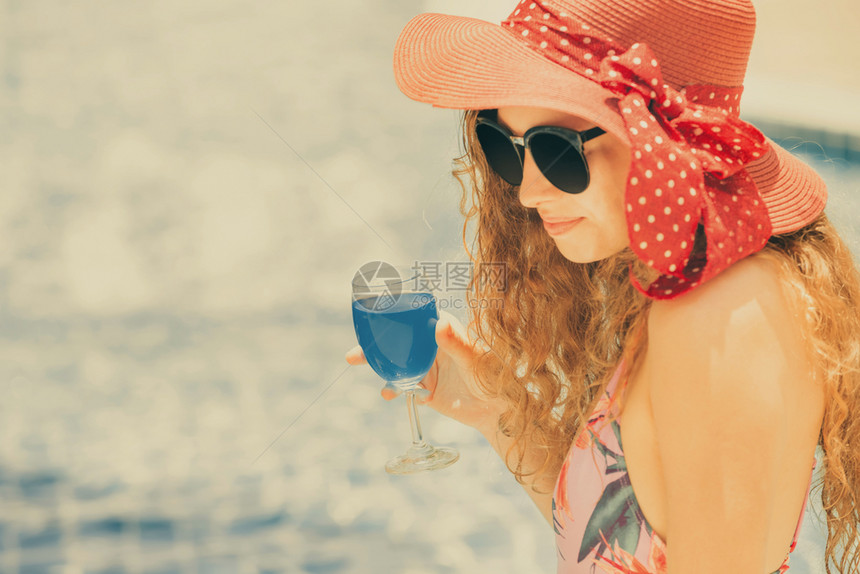 穿着泳衣的年轻女子手持酒杯在度假村游泳池旁玩得很开心图片