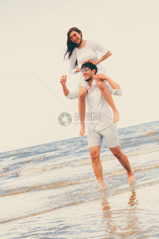 女友坐在男友肩膀上在沙滩玩耍图片