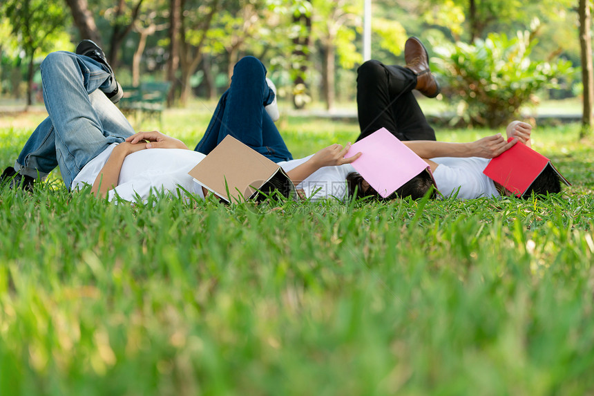 躺在草地上用书遮盖住脸的年轻人图片