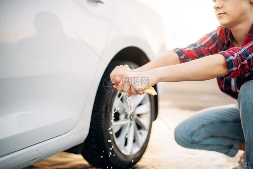 夏日洗车女在户外洗车过程后挤压海绵图片