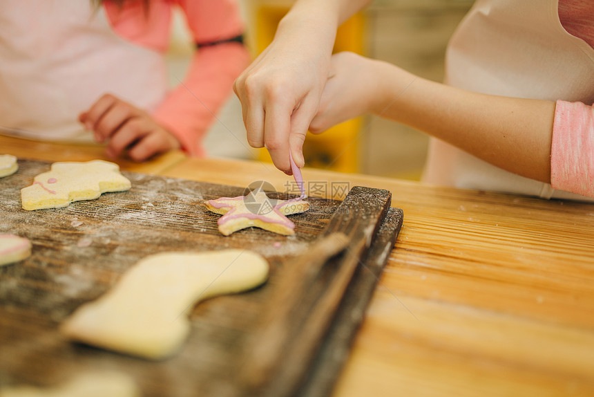 两个小女孩做糕点把饼干盖上甜层图片