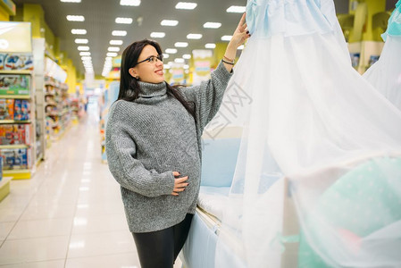 在商店中选择婴儿床位的孕妇图片
