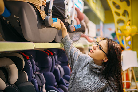 孕妇在商店中挑选儿童汽车安全座位图片