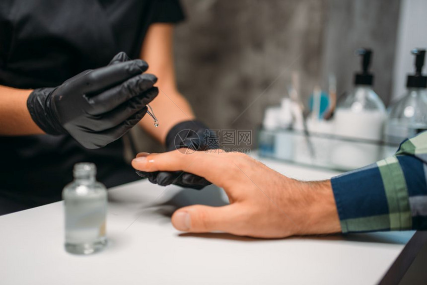 戴着黑手套的美容师为顾客做手部美甲护理图片