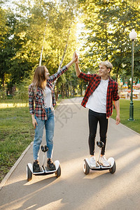 青年男女在公园里行驶平衡车并击掌图片