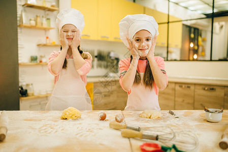 两个小女厨师用面粉抹脸厨房做饼干图片