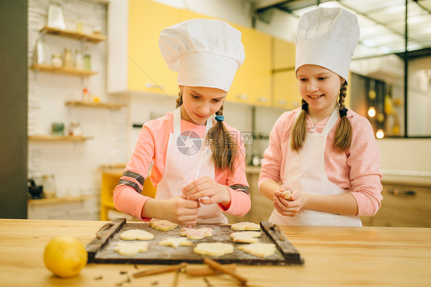 两个小女孩做厨师准备把饼干送进烤箱图片
