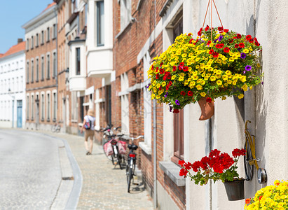 夏季欧洲城市Cozy街上装饰鲜花的古老建筑外墙与自行车和游客图片